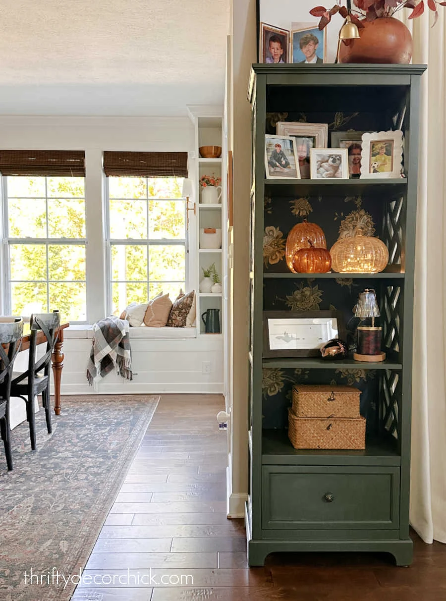 tall green bookshelf with wallpaper